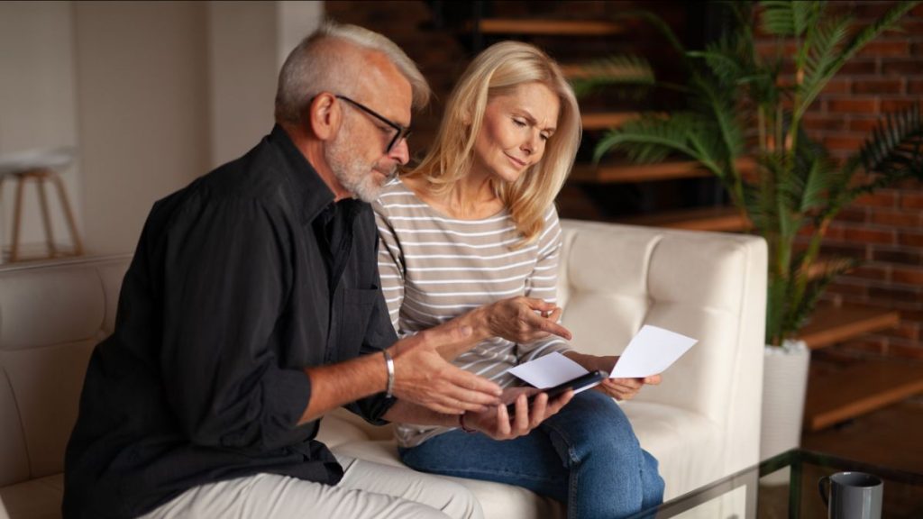 man and woman reviewing life insurance paperwork on sofa